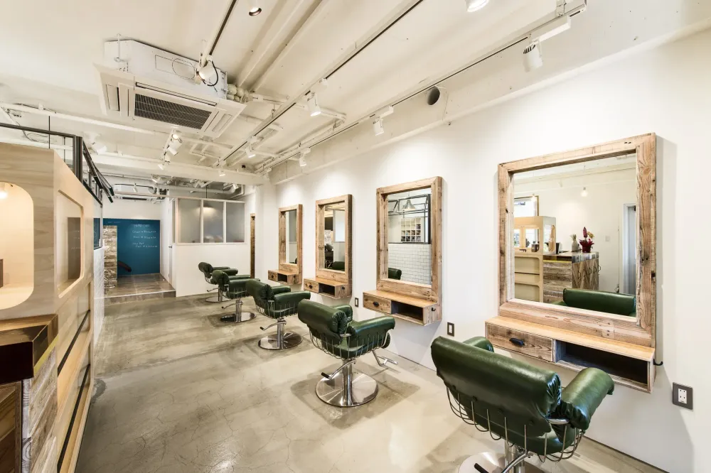 barber shop or salon interior with green leather chairs and rustic wood features. a mitsubishi electric HVAC unit is mounted on the ceiling providing comforting heat and refreshing cool to customers every day of the year